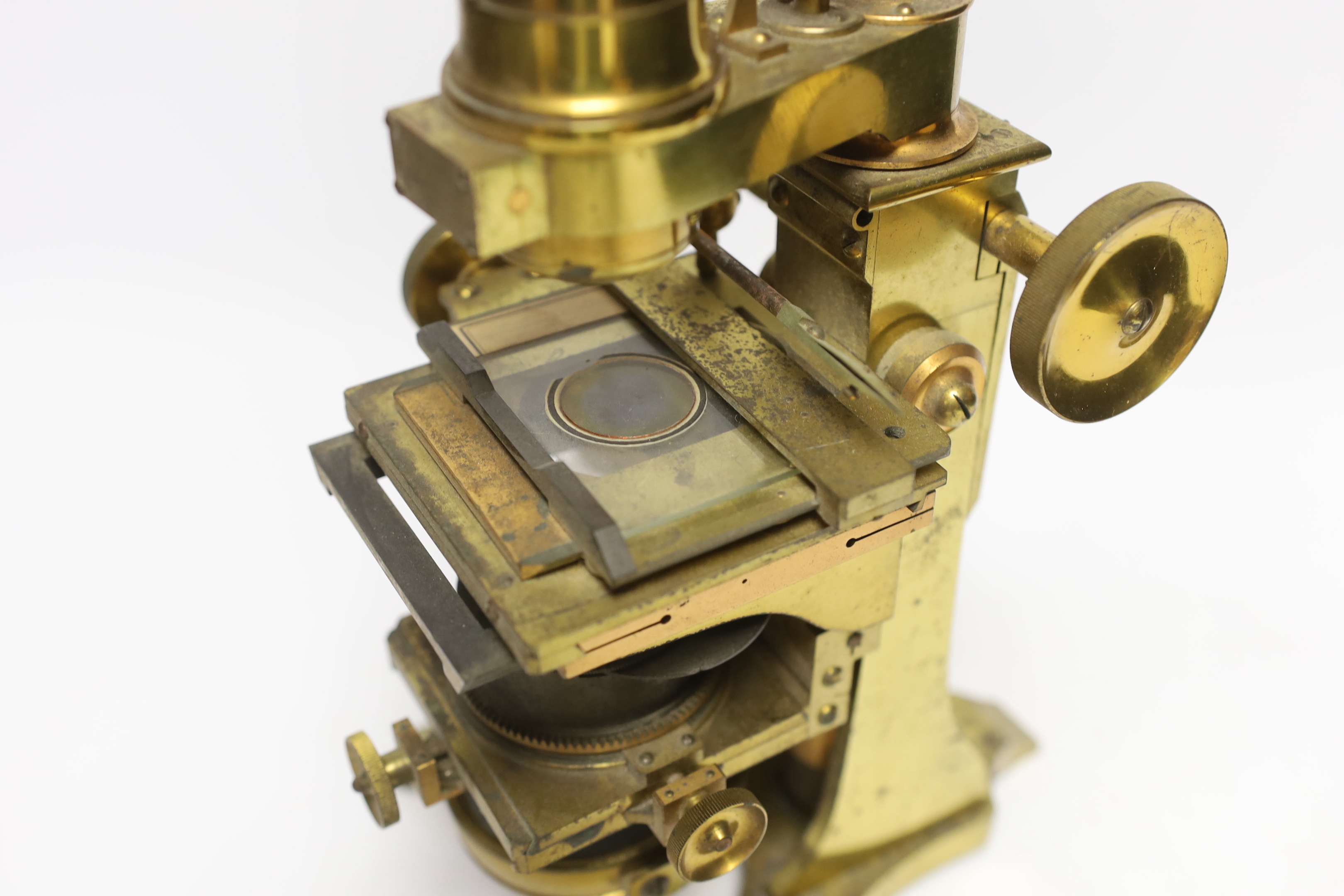 A brass microscope with mahogany box by A. Ross of London, dated 1890 to foot, with some unusual features including a rotating box under the bed for lens, box with fitted interior containing additional lens and other att